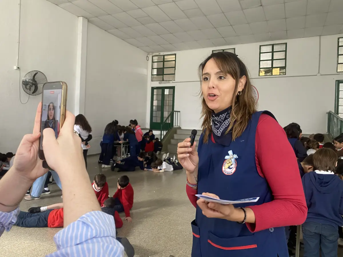Una profesional de Aterym Alta Gracia habla con micrófono a los niños de primaria durante la jornada del proyecto en la escuela